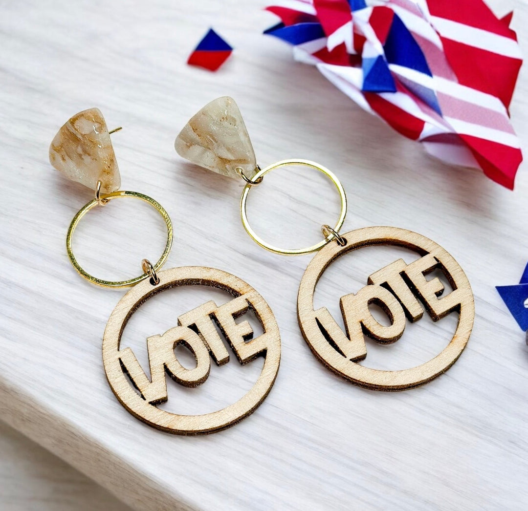 The Dappled Wood's Verity earrings which use a hypoallergenic 18k gold filled post and a wooden piece with the word VOTE inside a circle.