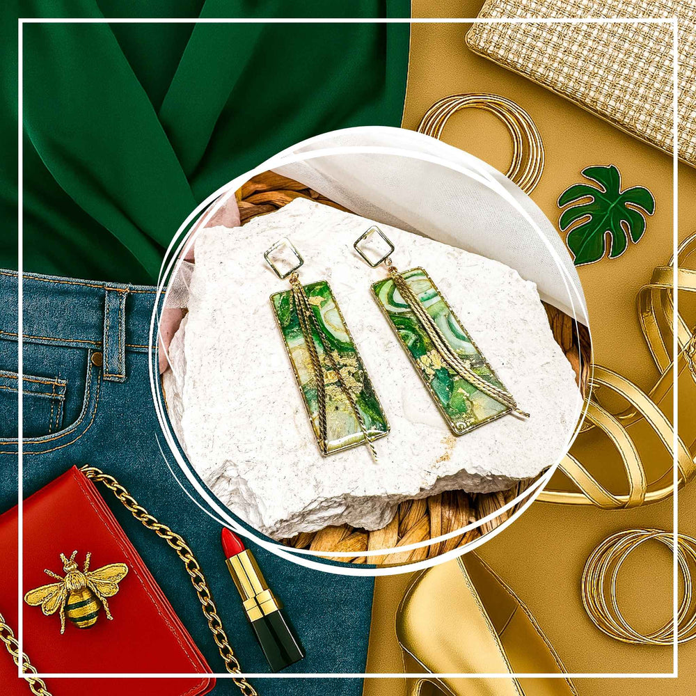 The Dappled Wood's Athena green and gold statement earrings from the Gilded Grove Collection, styled with a green blouse, high-waisted jeans, gold heels, red lipstick, a bee brooch, red clutch, and gold bangles for a girls' night out.