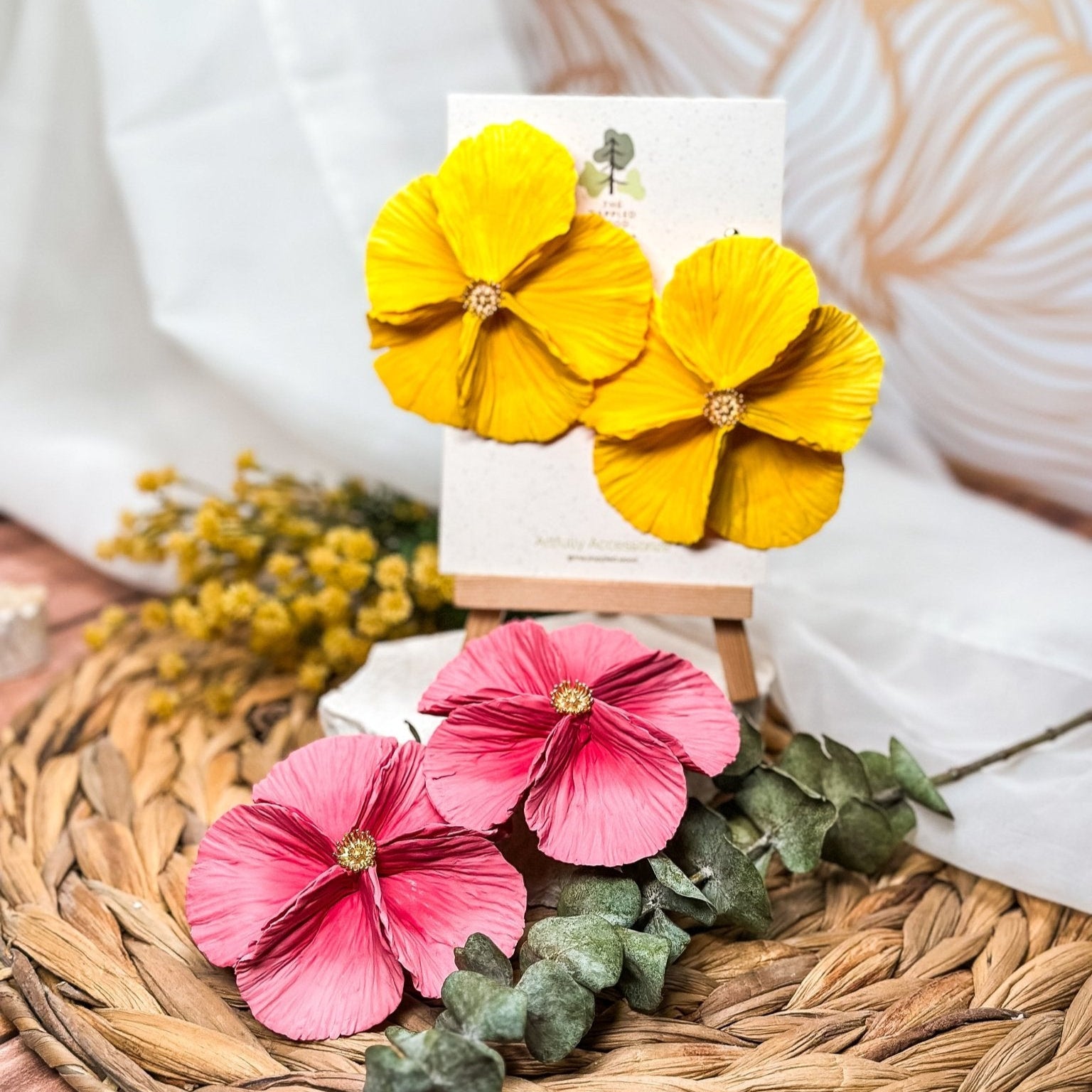 The Dappled Wood's Sabine polymer clay flower earrings in Tulip and Sunshine, shown side by side. The Tulip pair features a dusty pink gradient, while Sunshine glows in a golden yellow hue. Bold floral clay earrings and lightweight statement jewelry, perfect for garden parties or summer celebrations.