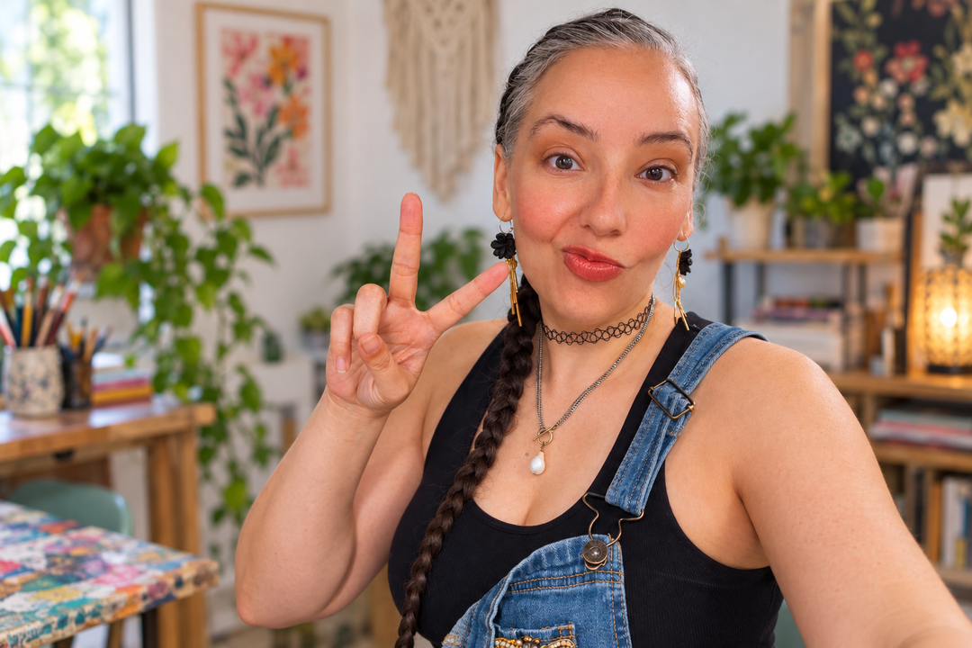 Brittany wearing denim overalls and handmade black floral statement earrings in her colorful studio