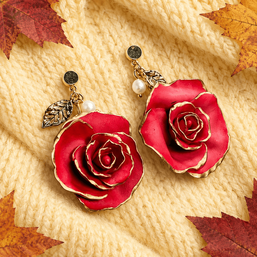 Red sculpted rose statement earrings on a butter yellow sweater with autumn maple leaves