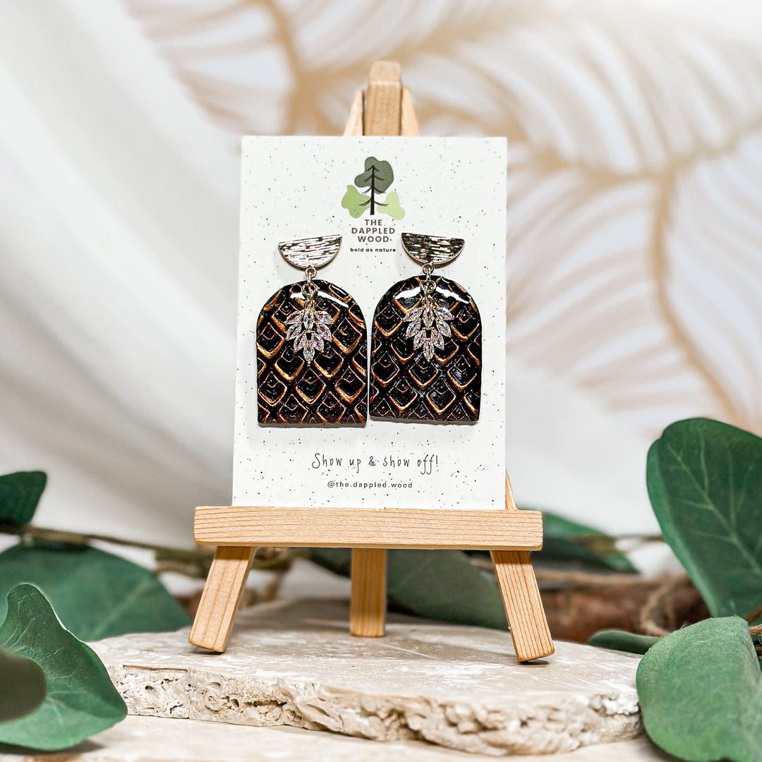 Black and gold polymer clay arch earrings with an intricate pattern, featured in The Dappled Wood’s New Years 2025 collection.