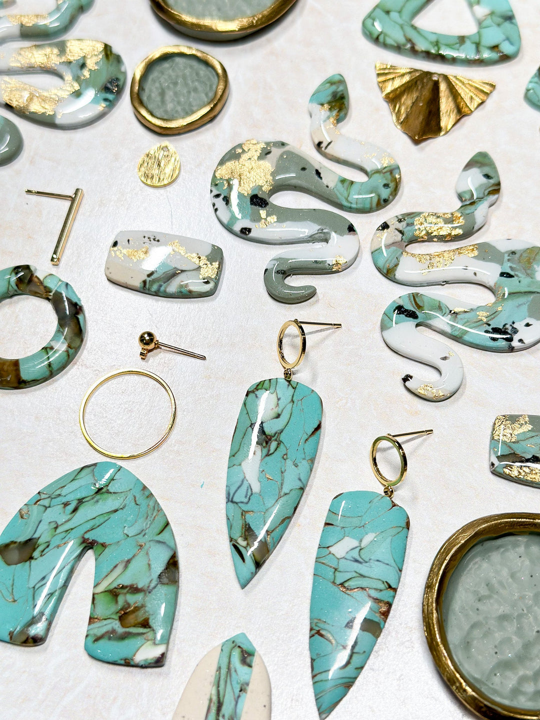 Flat lay of The Dappled Wood’s best-selling handcrafted turquoise polymer clay earrings with gold accents.