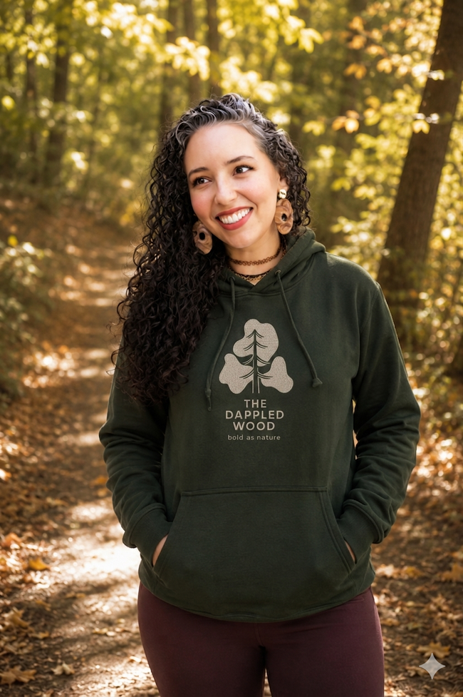 Brittany Arnett, founder of The Dappled Wood, standing outdoors in a green hoodie.