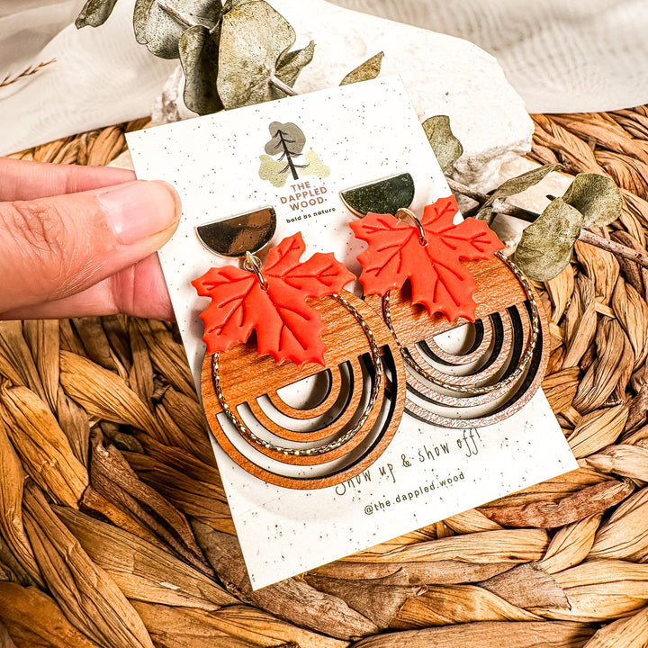 Burnt orange polymer clay maple leaves layered over circular real wood charms