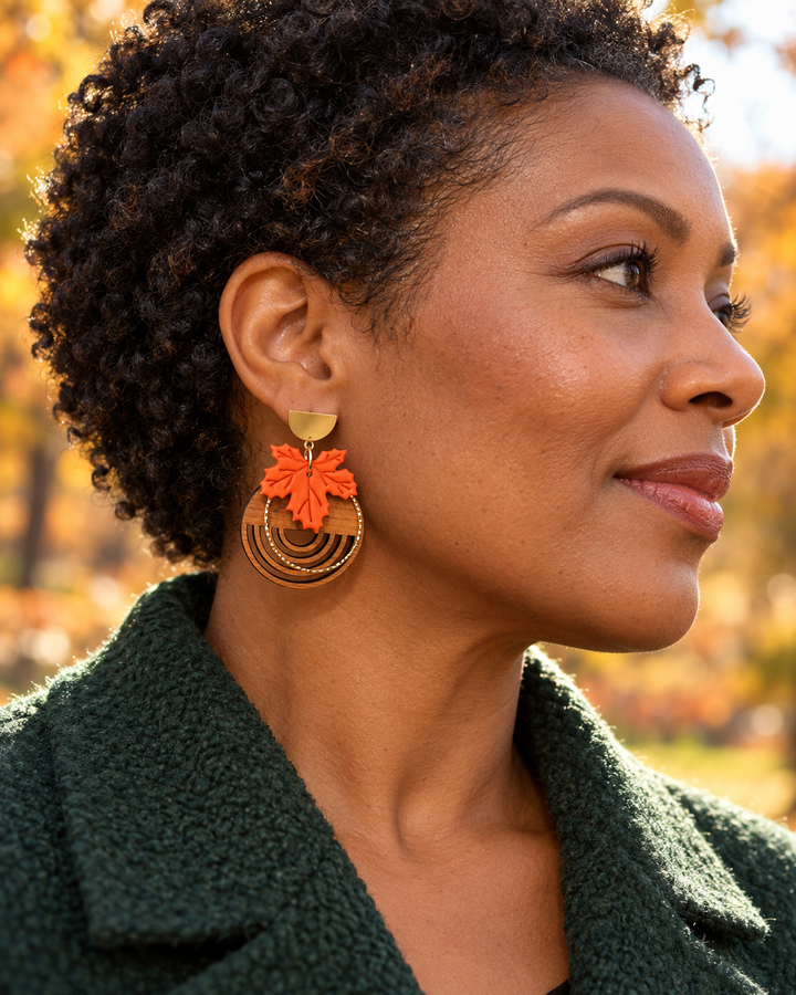 Black woman wearing Arden burnt orange maple leaf and real wood earrings outdoors