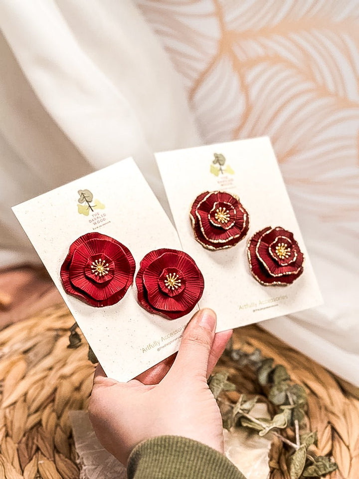 Circular floral statement stud earrings by The Dappled Wood in layered red and burgundy with gold details.