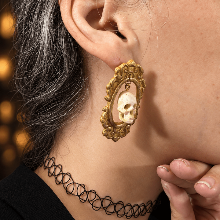 Close side view of Drusilla framed skull statement earrings on a model