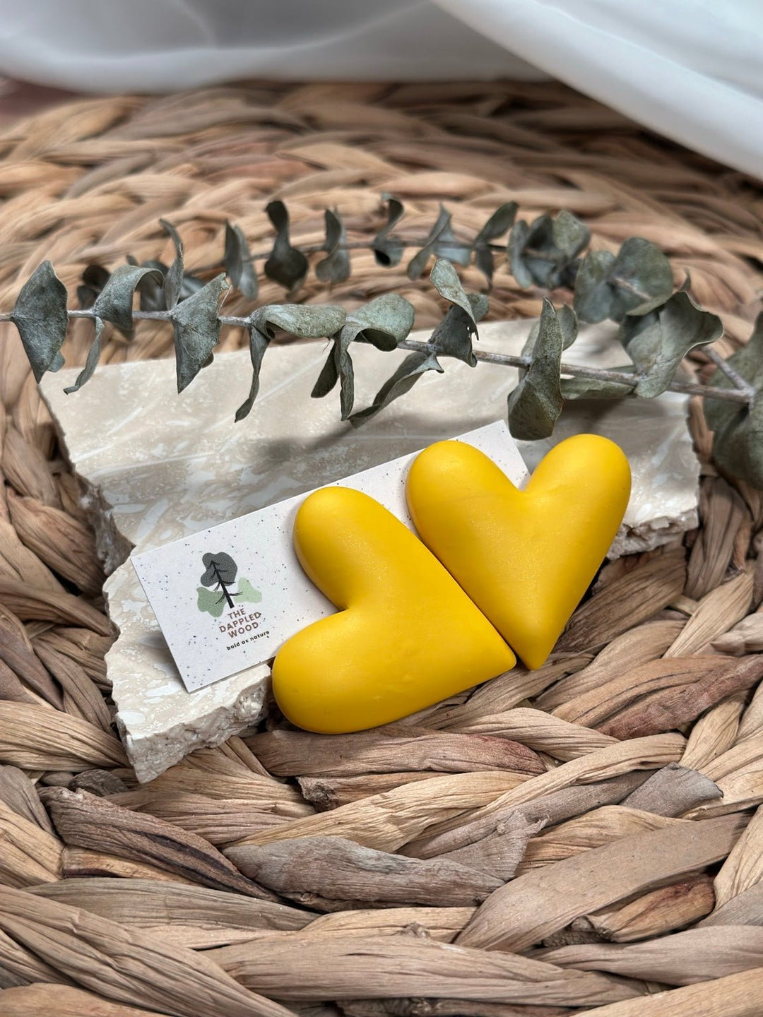 Extra large yellow puffy heart earrings by The Dappled Wood styled on woven natural textures.