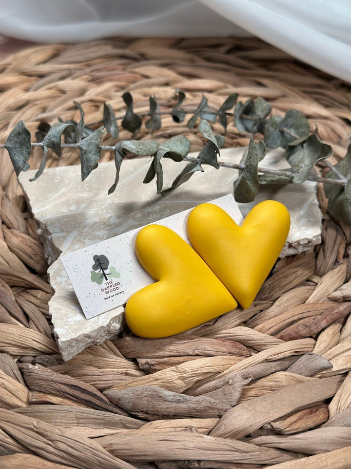 Extra large yellow puffy heart earrings by The Dappled Wood styled on woven natural textures.