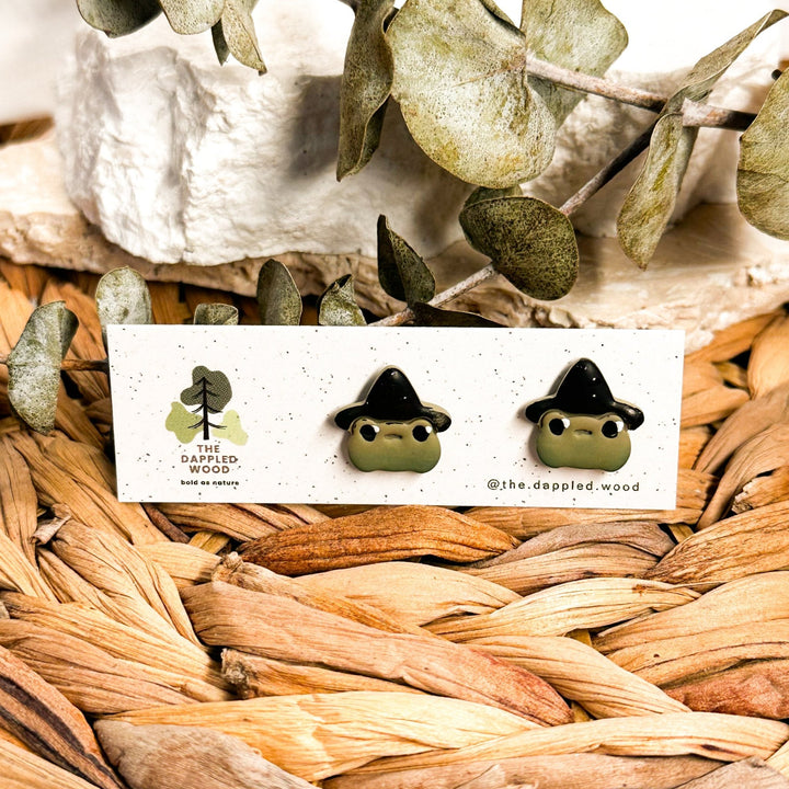 Green witchy frog Halloween stud earrings wearing black witch hats