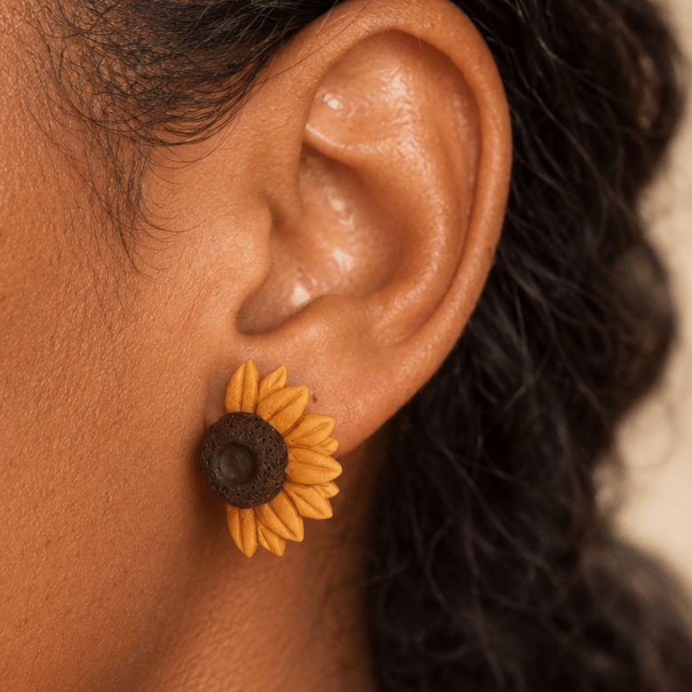 Close-up of a model wearing Jean half sunflower earrings with sculpted golden yellow petals and a textured brown center