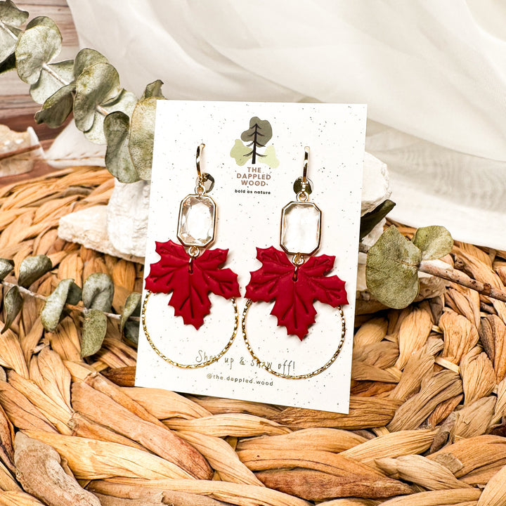 Lucinda red maple leaf earrings with faceted glass gems displayed on a branded card