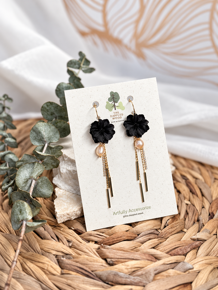 Black Martiza long tassel and freshwater pearl flower earrings by The Dappled Wood displayed on a branded card.