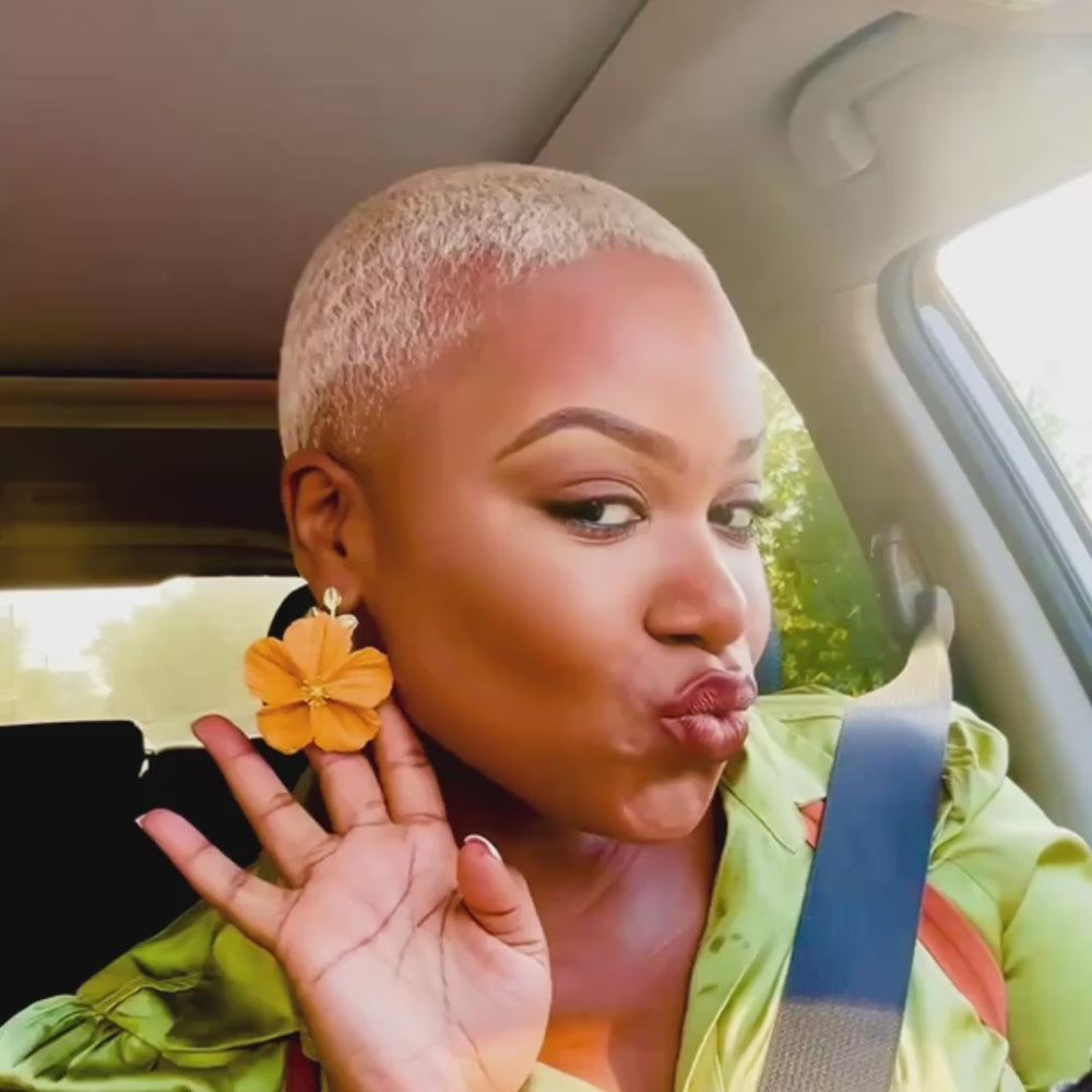 Customer wearing the Flora earrings in Golden Yellow from The Dappled Wood, sharing UGC in a car with a playful pose to highlight the bright floral design and lightweight style.