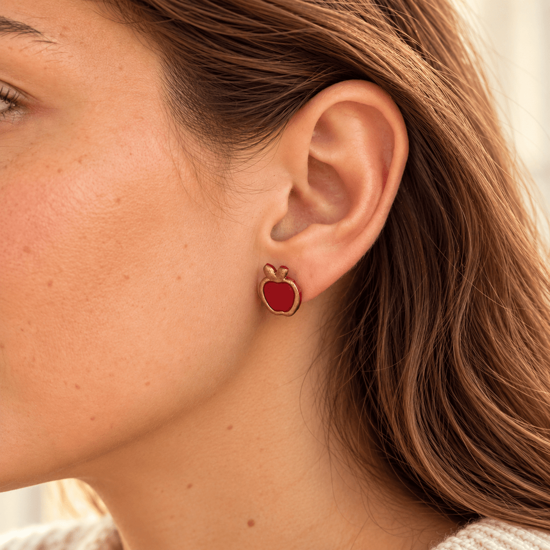 Close-up of model wearing red apple fall stud earrings with hand-painted gold edges
