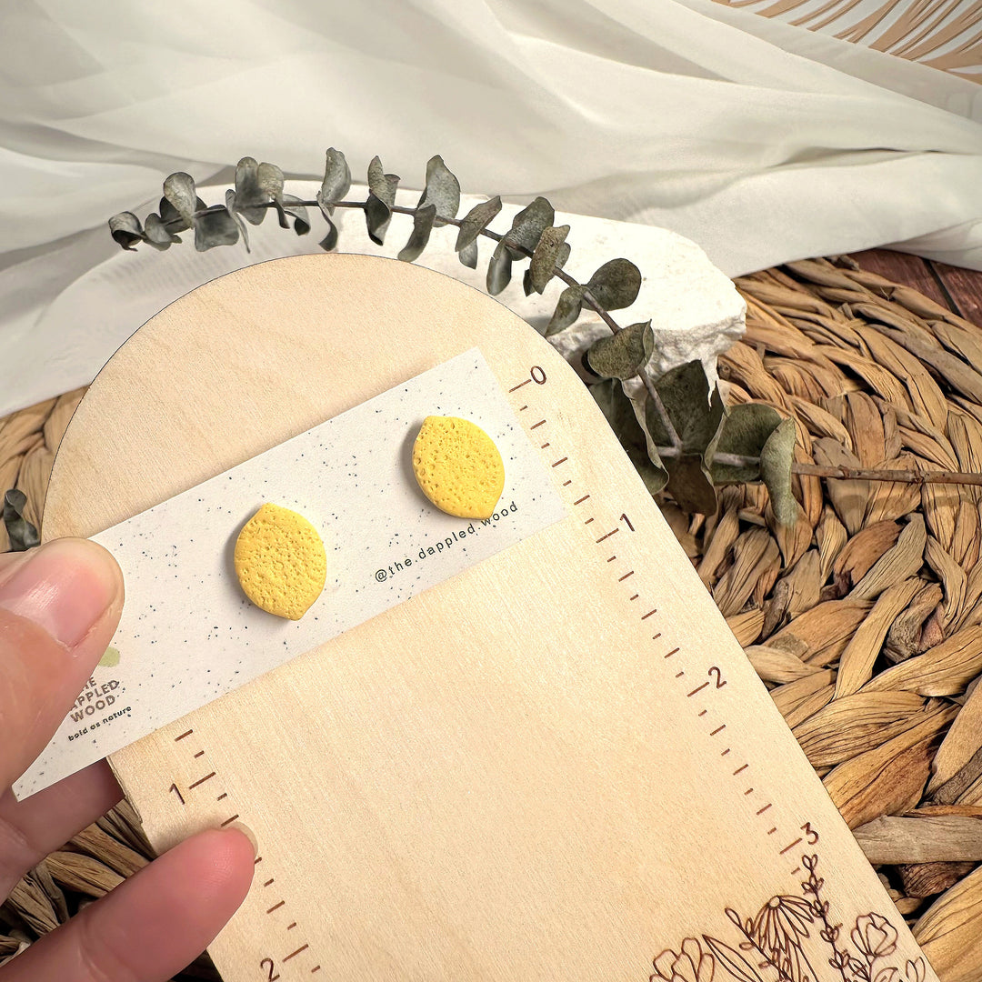 Leni lemon stud earrings shown beside measuring tape for scale