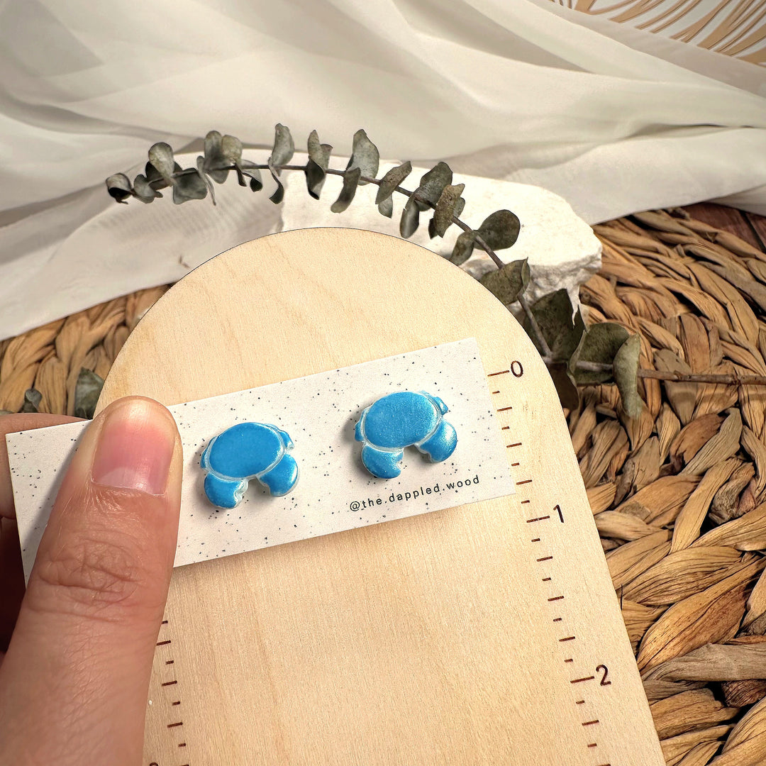 Nerissa crab stud earrings photographed beside measuring tape for scale