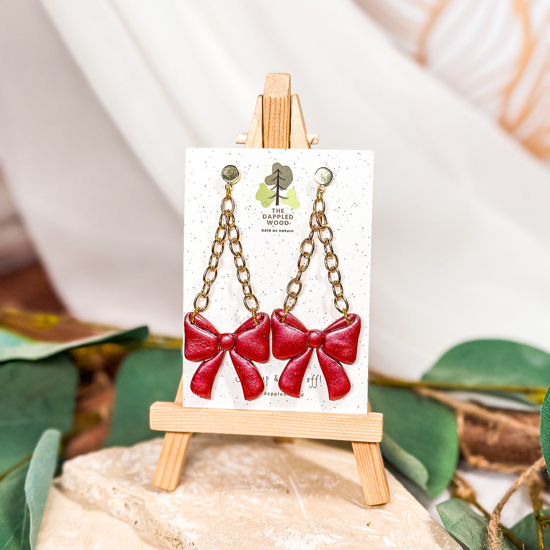 The Dappled Wood bow earrings from the Holidays 2023 collection featuring a festive polymer clay design that’s lightweight and comfortable for sensitive ears.