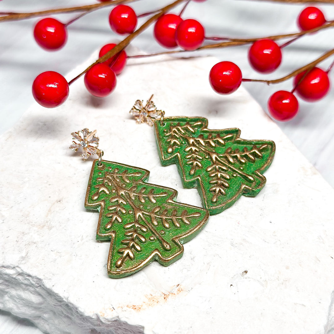 The Dappled Wood Geraldine Christmas tree earrings, handcrafted polymer clay holiday earrings with gold-embossed details on a deep green base. Finished with CZ snowflake stud posts, these lightweight statement earrings are perfect for festive celebrations.