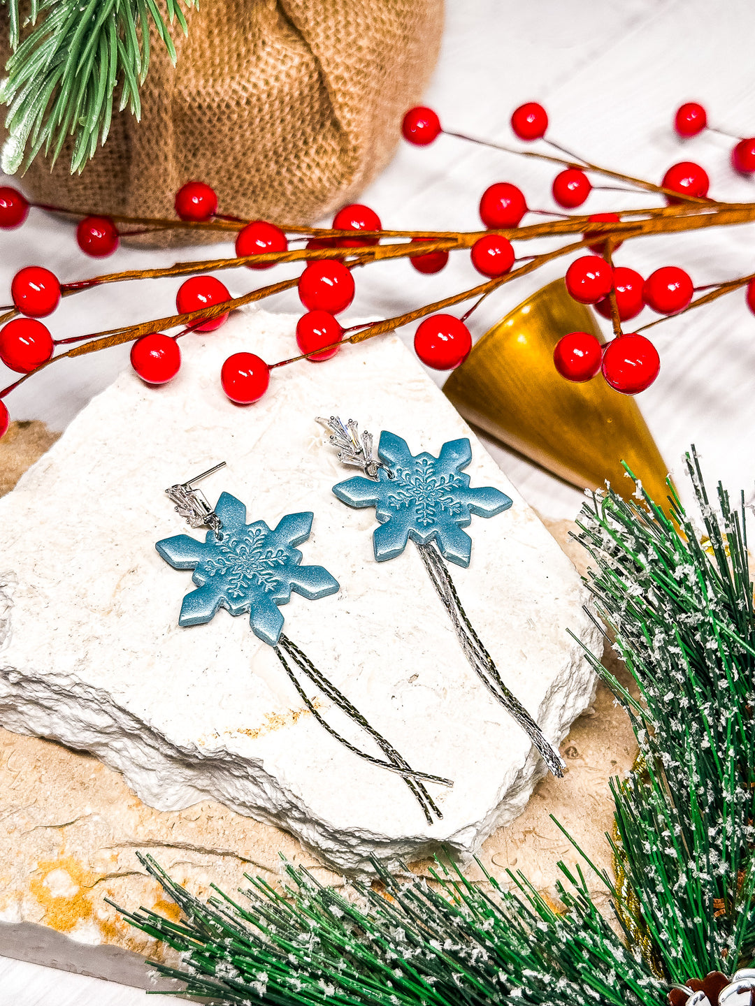 The Dappled Wood Holly Jolly blue snowflake earrings, featuring a delicate chain on CZ silver posts. A shimmering winter-inspired statement accessory.