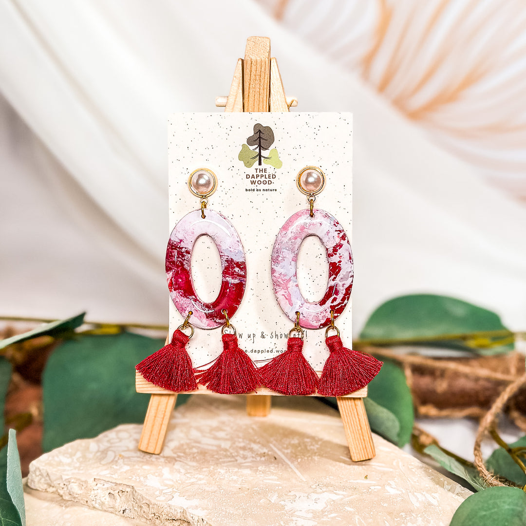 The Dappled Wood Holly Jolly red and white donut earrings with red tassels on a faux pearl post, a fun and festive Christmas accessory.