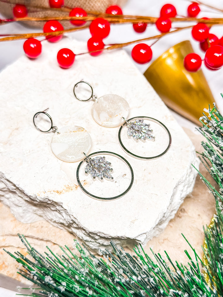 The Dappled Wood Holly Jolly silver CZ charm earrings, set in a silver hoop with a hollow circle post for a modern holiday touch.