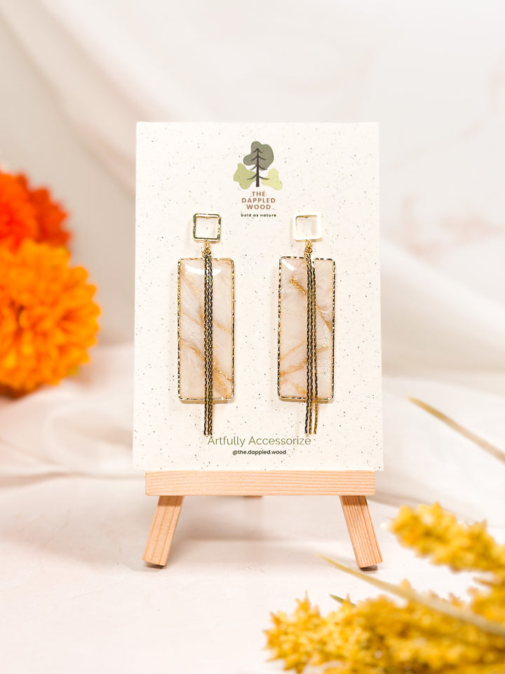 The Dappled Wood Ivory Coast large rectangle earrings, framed with a bold yet lightweight design, suspended on hollow square posts. A sophisticated geometric accent.