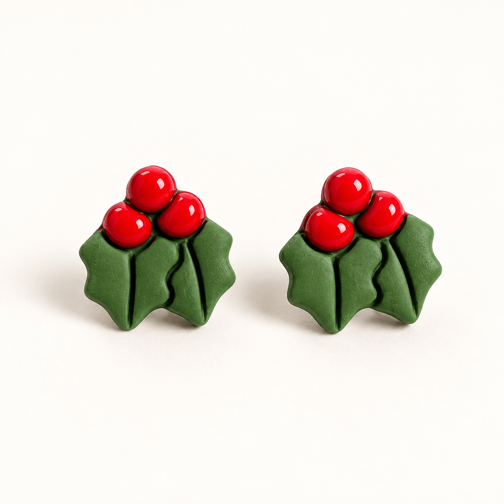Agnes handmade holly leaf studs with three red berries and two green leaves on white.