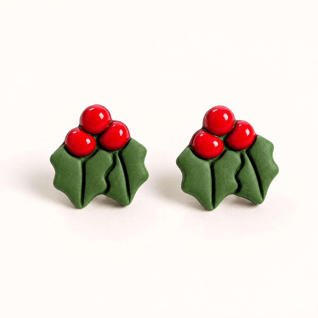 Agnes handmade holly leaf studs with three red berries and two green leaves on white.