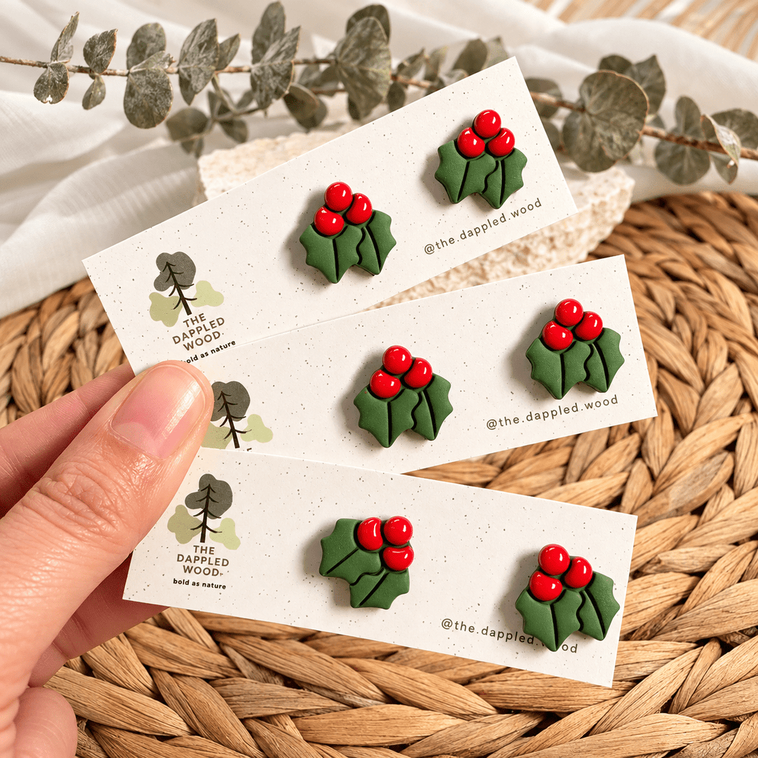 Agnes green holly leaf stud earrings with glossy red berries on cards.