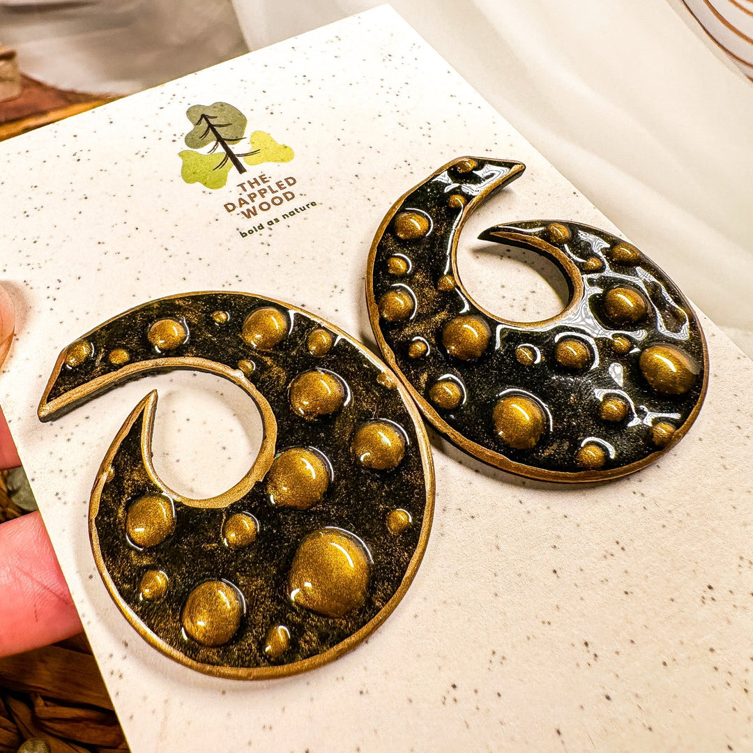 Model wearing Bronte black and gold sculptural spiral statement stud earrings