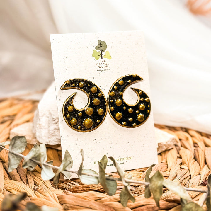 Model wearing Bronte blue and gold sculptural spiral statement stud earrings