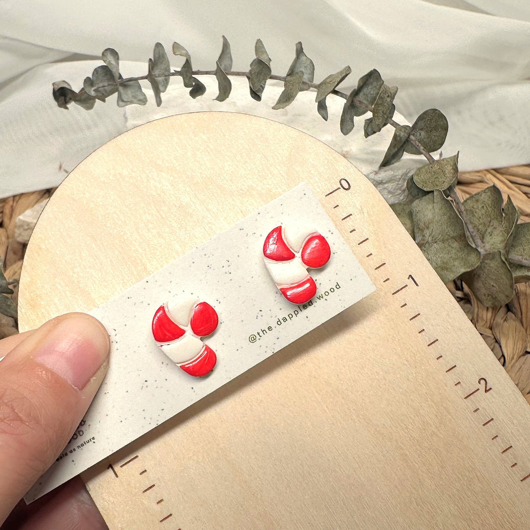 Claudette candy cane stud earrings shown beside measuring tape for scale