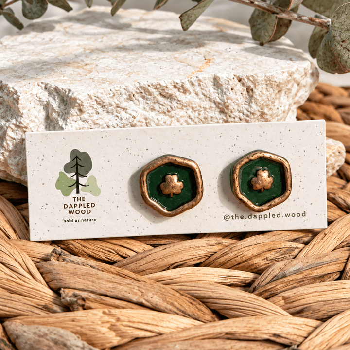 Felicity green and gold hexagonal clover stamp stud earrings on a display card.