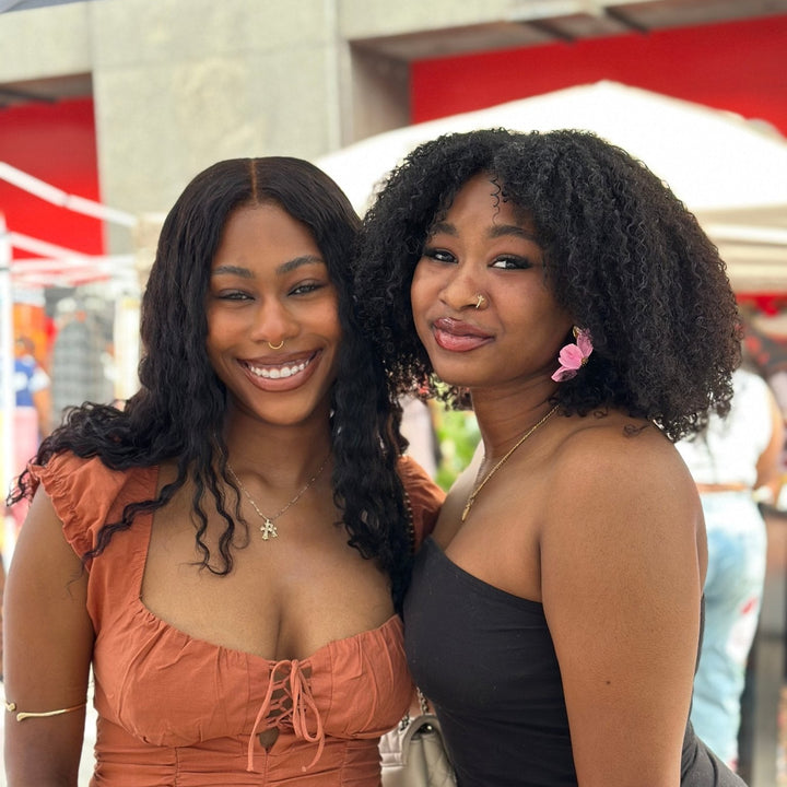 Two customers at an outdoor market, one wearing The Dappled Wood Flora flower earrings in pastel pink.