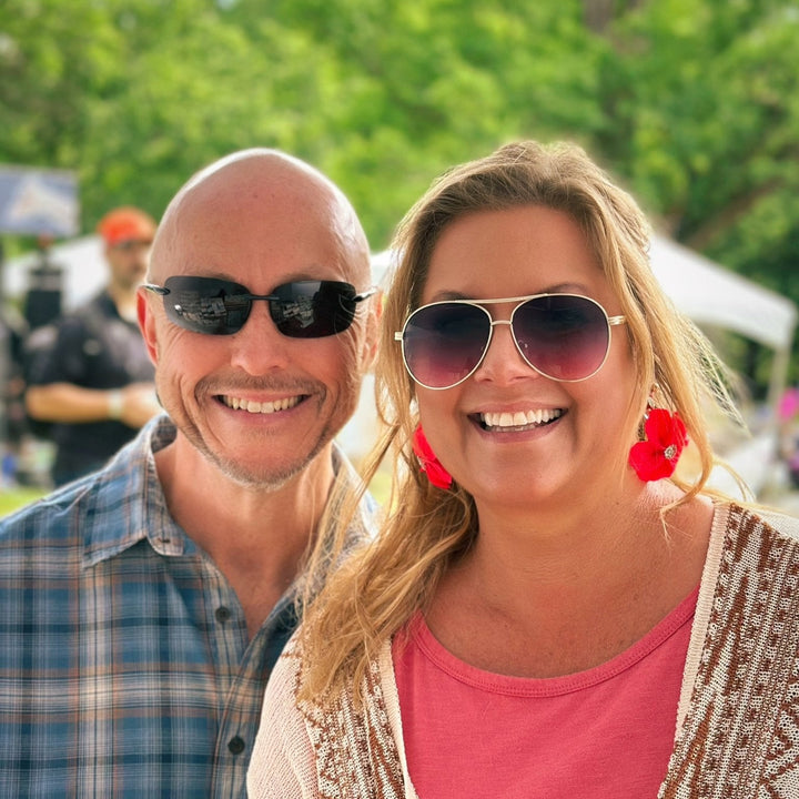 Two customers smiling outdoors, with one wearing The Dappled Wood Flora flower earrings in hot pink.
