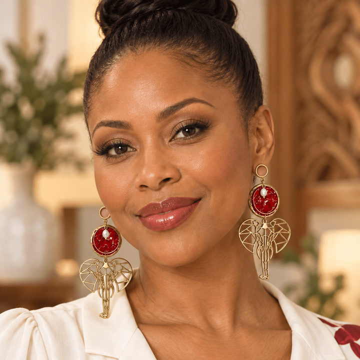 Woman wearing red and gold Dina elephant shoulder-duster earrings with pearl accents.