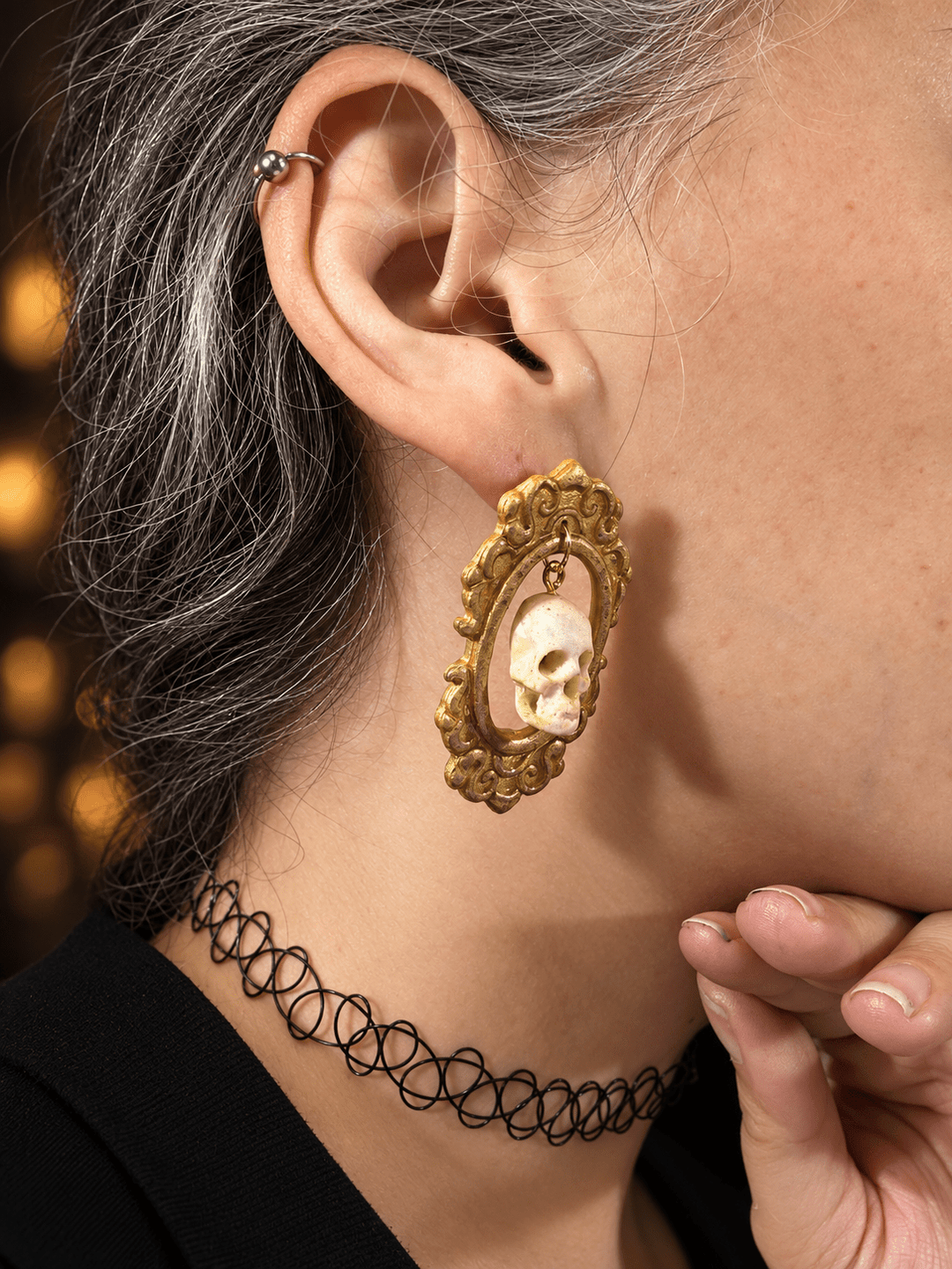 Close side view of Drusilla framed skull statement earrings on a model