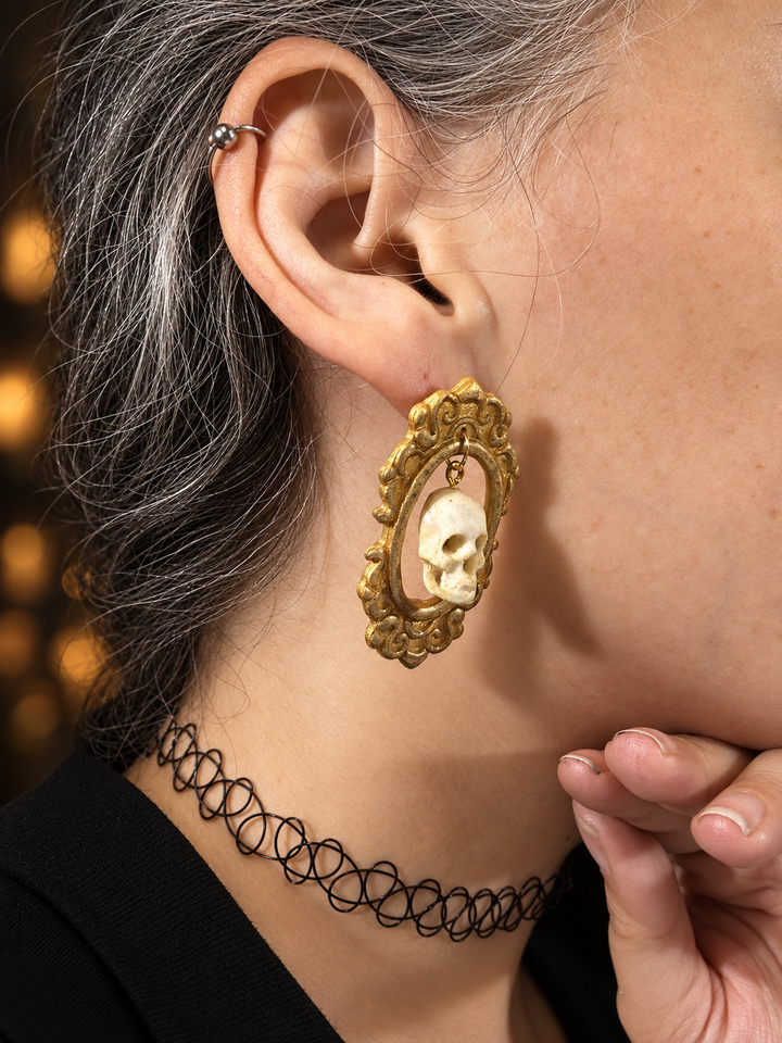 Close side view of Drusilla framed skull statement earrings on a model