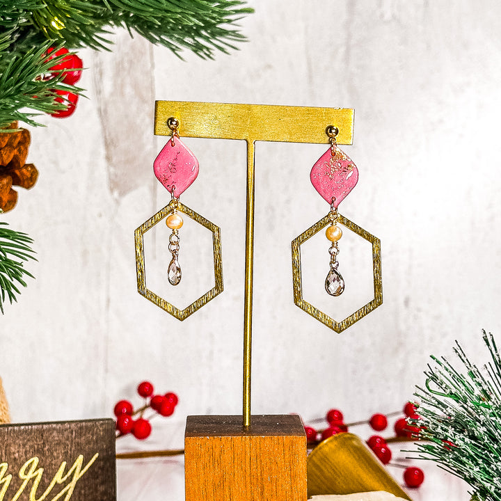 Pink diamond earrings accented with a large brass hexagon, pearl, and glass charms, part of The Dappled Wood’s Fall 2024 Pinktober collection.