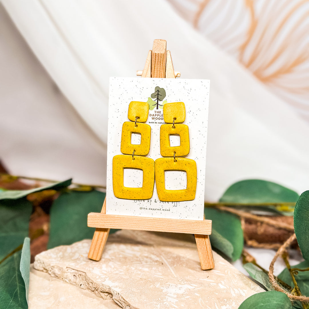 The Dappled Wood Oakley one-of-a-kind earrings from the Fall 2024 collection featuring a matte speckled canary yellow polymer clay design, suitable for sensitive ears.