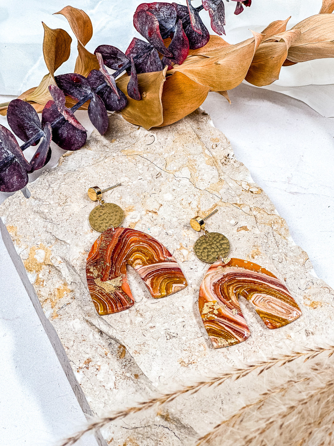 The Dappled Wood’s Traces of Tangerine faux orange agate statement earrings featuring a chunky arch with a dappled brass connector and gold flat circle post. Nature-inspired lightweight jewelry, perfect for fall fashion.