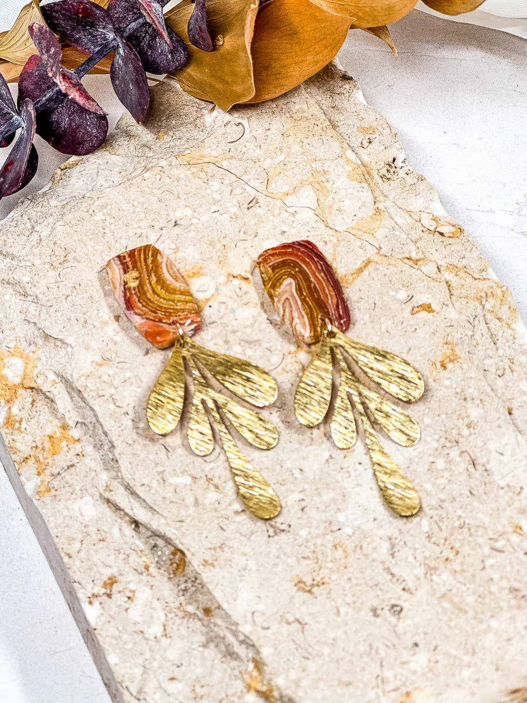 The Dappled Wood’s Traces of Tangerine statement earrings featuring a rectangular shape with a large brushed brass leaf charm. A bold yet lightweight accessory for autumn fashion lovers.