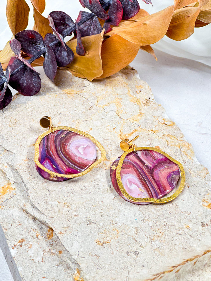 Organic circle earrings from The Dappled Wood’s Veins of Violet collection, featuring faux purple agate, brushed brass charms, and a gold flat circle post. Nature-inspired lightweight statement jewelry.