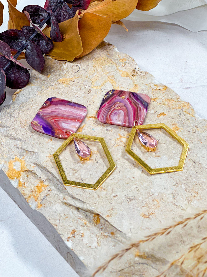 Slanted square earrings from The Dappled Wood’s Veins of Violet collection, showcasing faux purple agate, brushed hexagon charms, and pink glass accents. Bold, lightweight jewelry.
