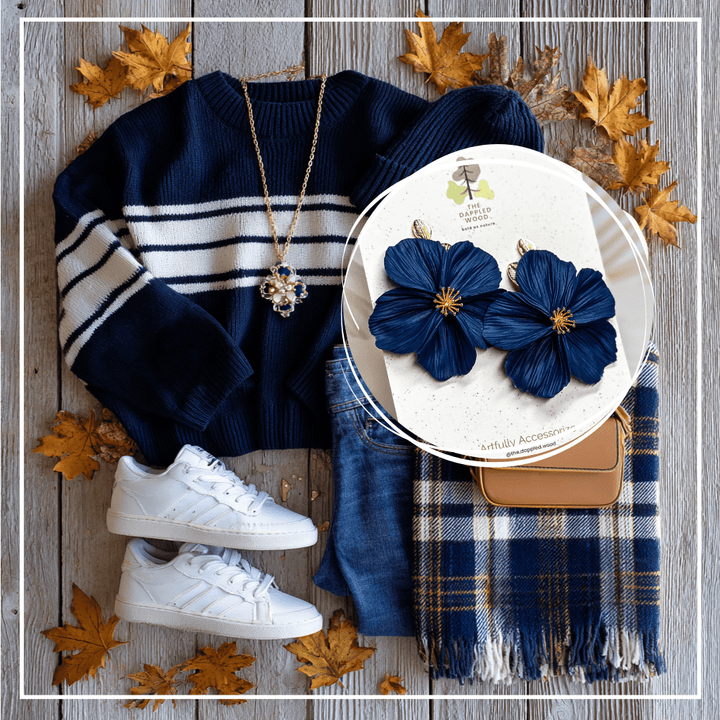 The Dappled Wood Fall 2025 Flora earrings in navy blue jewel-toned flowers, styled in a homecoming outfit flatlay with a striped sweater, plaid scarf, jeans, sneakers, and seasonal accessories, perfect for fall homecoming events and autumn celebrations.