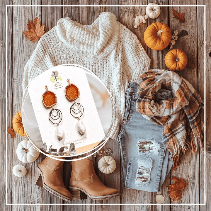 Flatlay of The Dappled Wood Fall 2025 collection featuring Rhea pumpkin orange faux baroque pearl statement earrings styled with a cozy sweater, skirt, scarf, and fall accessories for a pumpkin patch outfit.