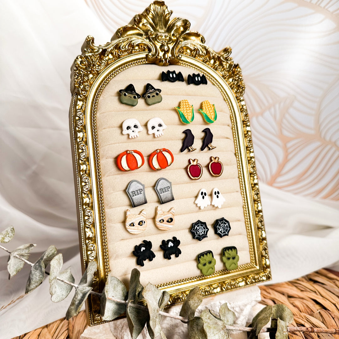 Falloween stud earrings in a gold frame, including bats, witchy frogs, pumpkins, ghosts and mummy cats.