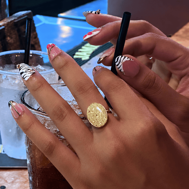 Customer wearing a golden yellow Gemma statement ring by The Dappled Wood with a patterned manicure at a bar.